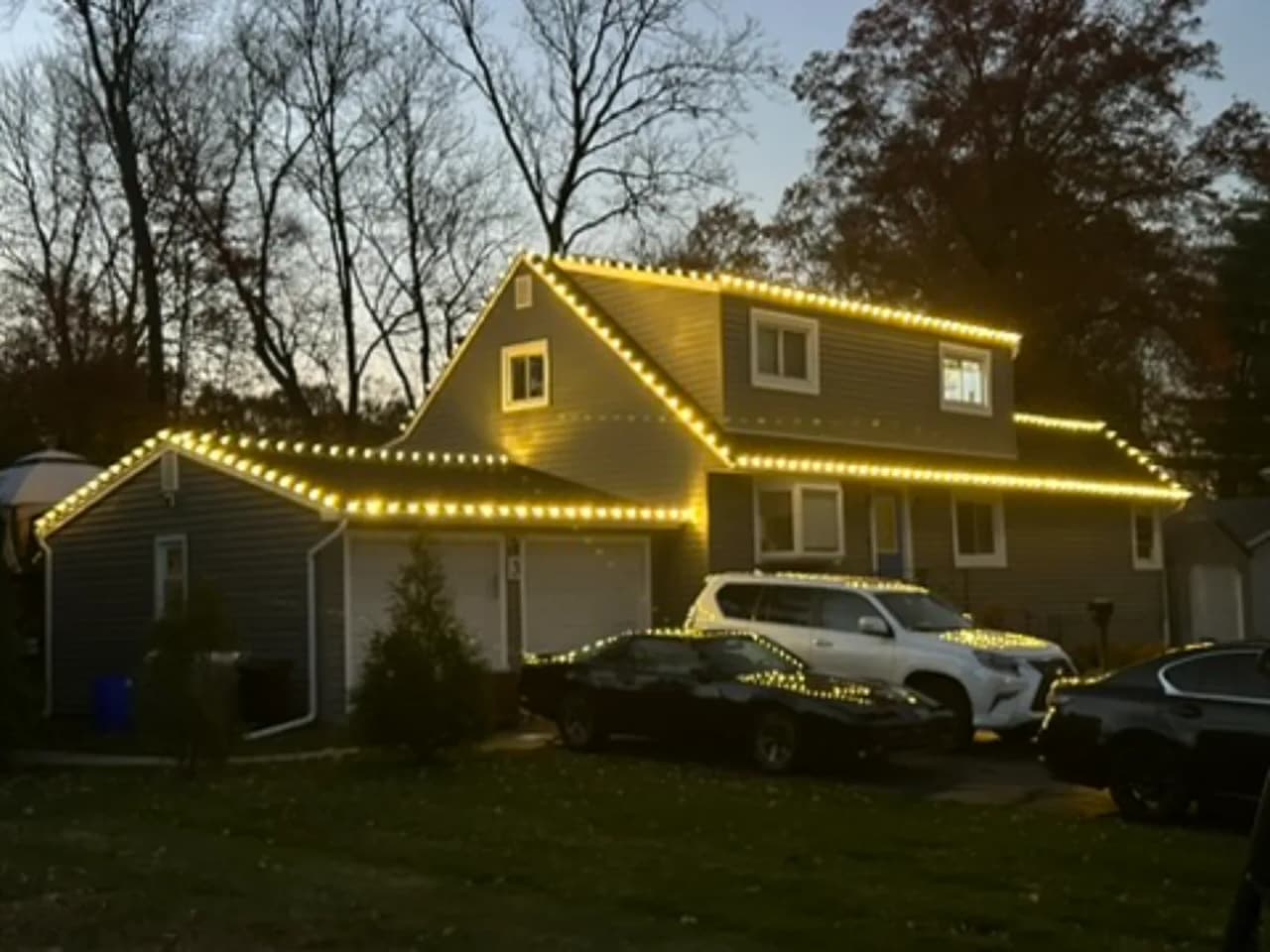Ranch home outlined with warm white Christmas lights at dusk