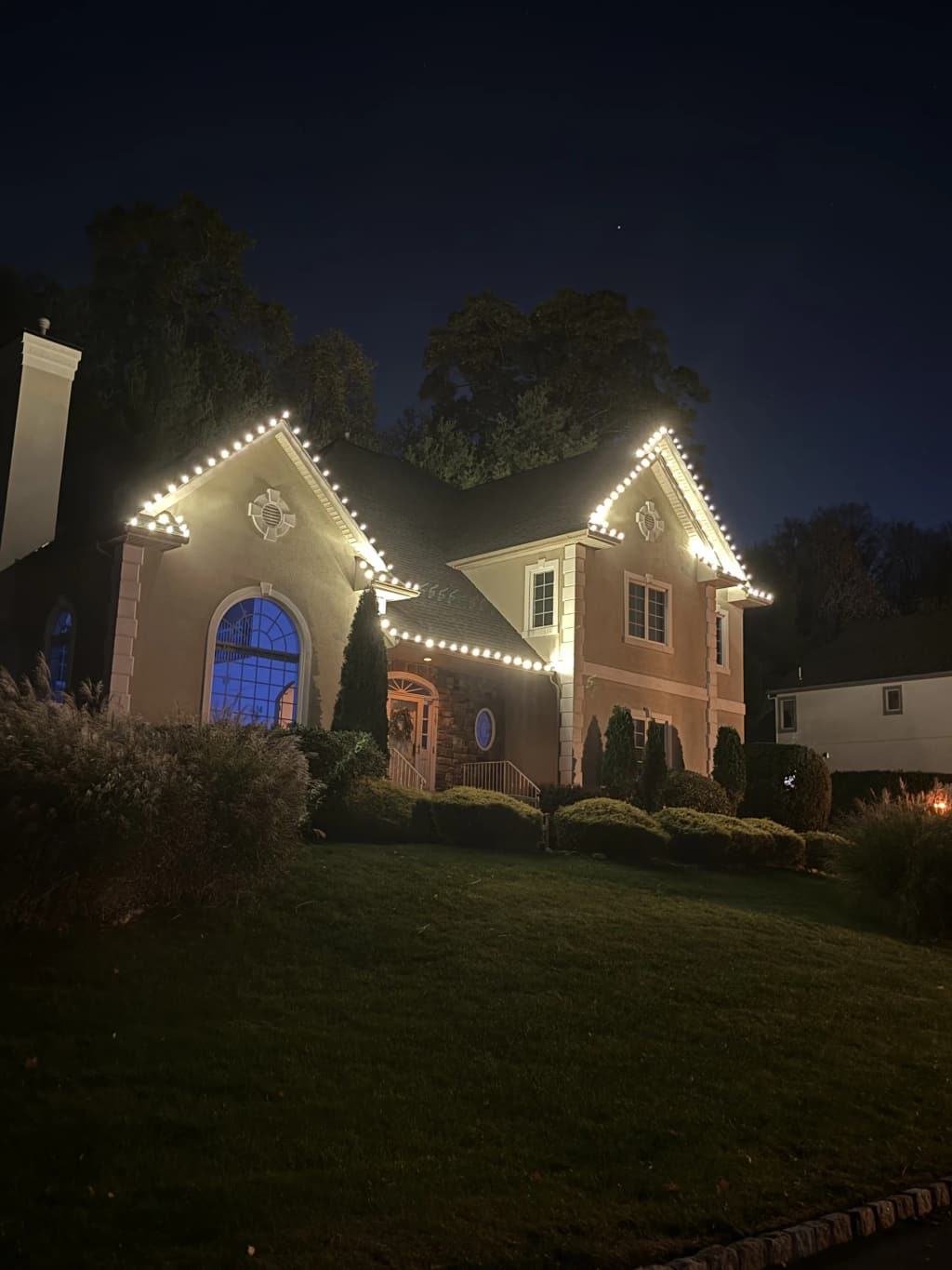 Brick home outlined with a complete warm white holiday-lighting display