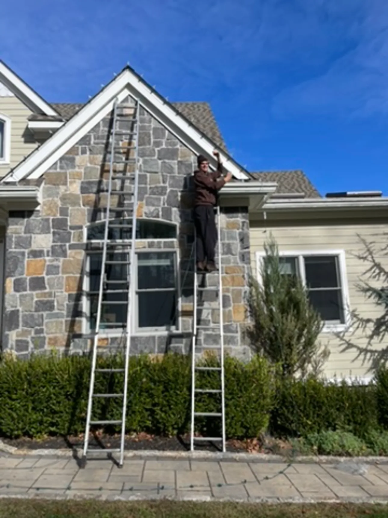 Brightline technician installing lights on a stone gable